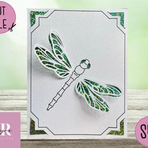 May include: A white card with a green glitter border and a black and white outline of a dragonfly with green glitter wings. The card has the text "SVG" in the bottom right corner.