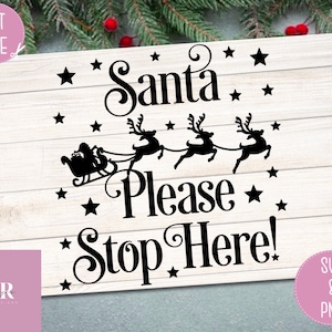 Op de afbeelding: Een zwart-wit bord met de tekst "Santa Please Stop Here!" met een silhouet van Sinterklaas in een slee die door rendieren wordt getrokken. Het bord is op een witte houten achtergrond met sterren.