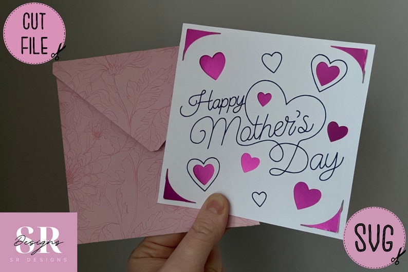 May include: A white card with the text "Happy Mother's Day" in black cursive script. The card is decorated with pink hearts and a pink envelope with a floral pattern.