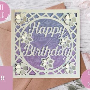 Op de afbeelding: Een witte kaart met een paarse en witte gepatroneerde achtergrond. De kaart heeft een cirkel uitgesneden met de woorden "Happy Birthday" erin. De cirkel is omgeven door een wit tralieontwerp en witte bloemen.