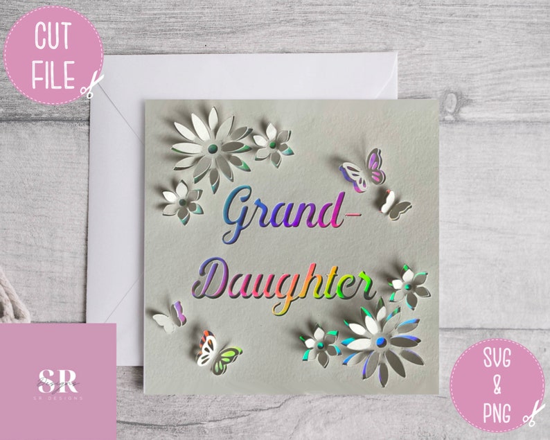 May include: A white card with a rainbow-colored text that says "Grand-Daughter" surrounded by cut-out flowers and butterflies.