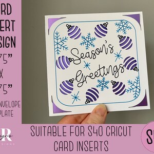 Può includere: Un biglietto bianco con un bordo blu e un design di ornamenti viola e bianchi. Il biglietto recita "Season's Greetings". Il biglietto misura 4,75 pollici per 4,75 pollici ed è adatto per un inserto per biglietti Cricut S40.