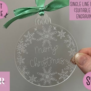 Könnte beinhalten: Ein transparenter Weihnachtsbaumschmuck aus Acryl mit einem einzeiligen Design aus Schneeflocken und dem Text "merry Christmas".