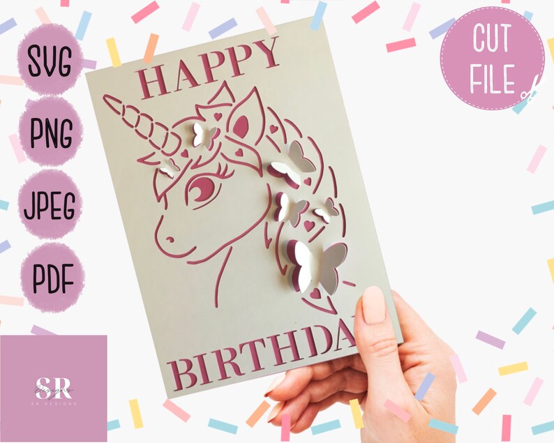 May include: A pink and white card with the text "Happy Birthday" and a cut-out design of a unicorn with butterflies. The card is being held by a hand.