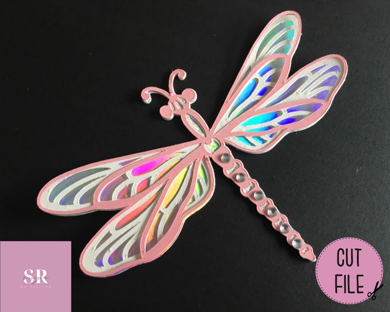 May include: A pink iridescent dragonfly cut file for crafting. The dragonfly has intricate details and a delicate design.