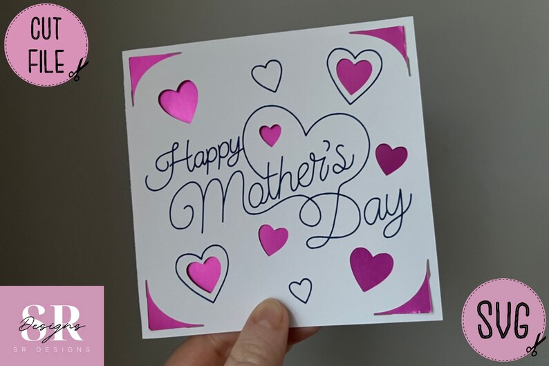May include: A white card with the text "Happy Mother's Day" in black cursive script. The card is decorated with pink hearts, some of which have a cut-out design.