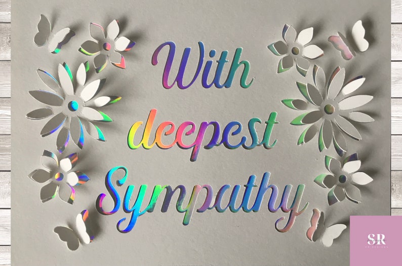 以下が含まれることがあります： 虹色の虹色の文字で「With deepest sympathy」と書かれた灰色のカード。カードは白い紙の花と蝶で飾られています。