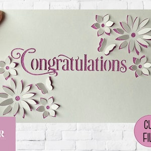 May include: A digital cut file for a greeting card featuring the word "Congratulations" in a decorative font with pink glitter, surrounded by white paper flowers and butterflies.