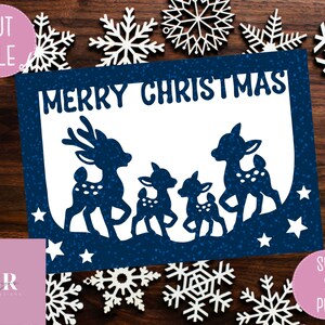 May include: A blue card with a white background and the text "Merry Christmas" in a white font. The card features a silhouette of three deer with white spots, standing on a blue background with white stars.