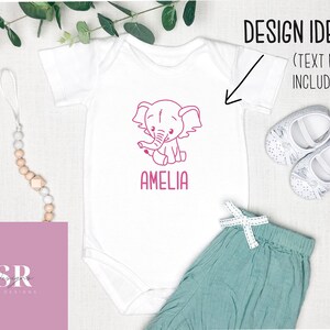 May include: White baby onesie with a pink outline of an elephant and the name Amelia printed below. The onesie is on a white background with a wooden bead necklace and a pair of white baby shoes.