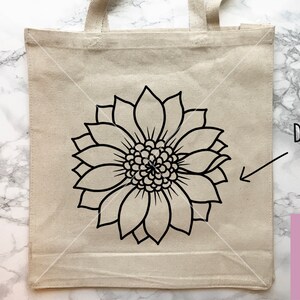 May include: A white tote bag with a black outline of a sunflower design. The text "DESIGN IDEA" is written on the right side of the bag.