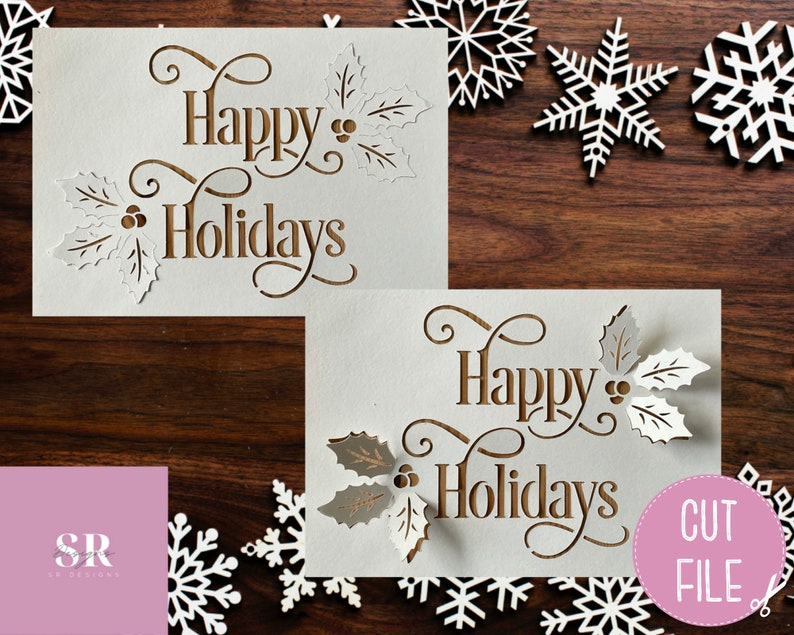 Puede incluir: Dos tarjetas blancas con el texto "Happy Holidays" en letras marrones y un dise&ntilde;o de hoja de acebo. Las tarjetas est&aacute;n sobre una superficie de madera marr&oacute;n con copos de nieve blancos esparcidos a su alrededor. El texto "CUT FILE" est&aacute; en un c&iacute;rculo rosa en la esquina inferior derecha.