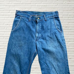 May include: A pair of blue denim jeans with a button fly and two front pockets.