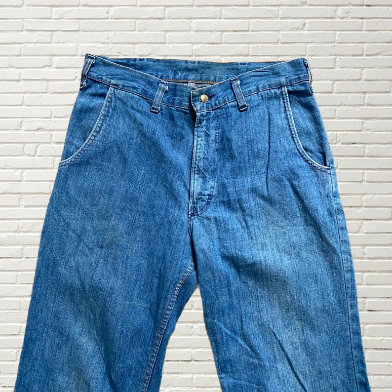 May include: A pair of blue denim jeans with a button fly and two front pockets.