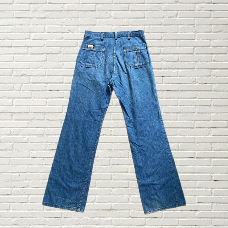May include: A pair of blue denim jeans with a wide leg style. The jeans have a high waist and a button fly.