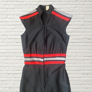 K&ouml;nnte beinhalten: Schwarzer &auml;rmelloser Jumpsuit mit einem roten und silbernen Streifen-Detail an Taille und Ausschnitt. Der Jumpsuit hat einen Rei&szlig;verschluss an der Vorderseite.