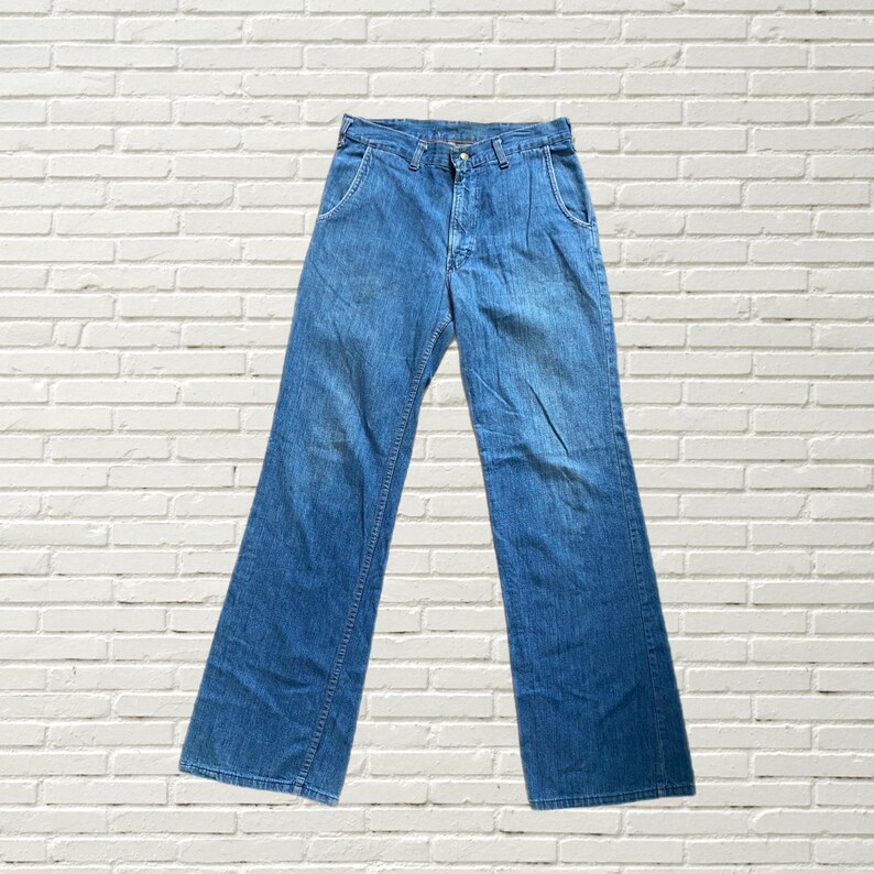 May include: A pair of blue denim jeans with a wide leg style. The jeans have a classic five-pocket design and a button fly.