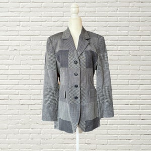 May include: A black and white patterned blazer with a button closure. The blazer has a collar and long sleeves.