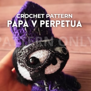 Peut inclure: Patron de crochet pour une poupée avec une capuche violette et un visage noir et blanc. Le texte "CROCHET PATTERN PAPA V PERPETUA" est affiché sur l'image. La poupée a des yeux noirs et est faite de fil.