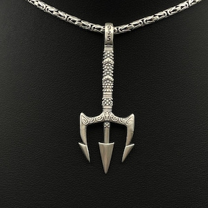 May include: A silver trident pendant necklace. The pendant is a detailed trident design with a textured handle and a pointed tip. The necklace chain is a linked design. The pendant is suspended from the chain.