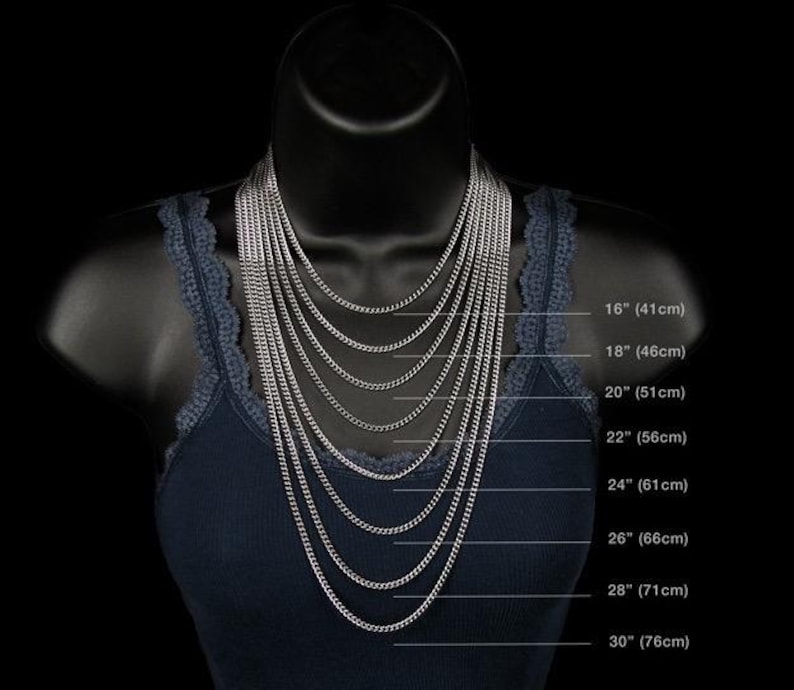 May include: A black mannequin displays a collection of silver chain necklaces of varying lengths. The necklaces range from 16 inches (41cm) to 30 inches (76cm) in length, showcasing different styles and layering options. The mannequin is wearing a navy blue tank top.