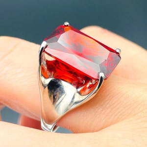 May include: A silver ring with a large, red, rectangular gemstone.