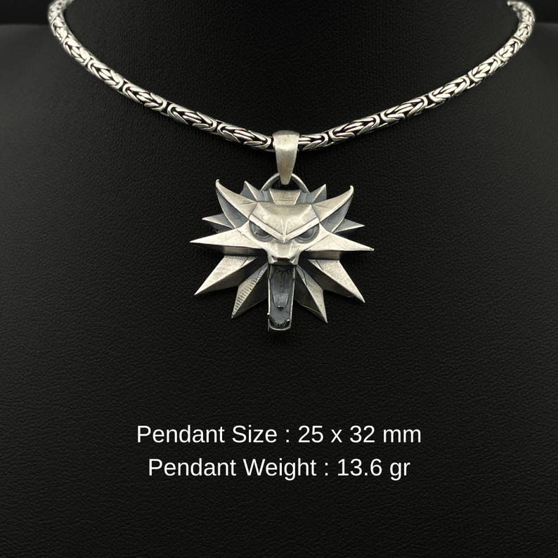 May include: Silver pendant necklace featuring a stylized wolf head design. The pendant is 25 x 32 mm and weighs 13.6 grams. The necklace has a detailed chain. The pendant is suspended from a silver chain. The text on the image reads: Pendant Size: 25 x 32 mm, Pendant Weight: 13.6 gr.