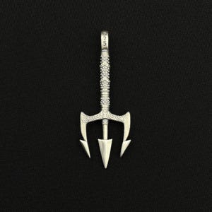 May include: A silver trident pendant with a detailed handle and three-pronged head. The pendant has a textured design and the number "925" is visible on the top. The pendant is displayed against a black background.