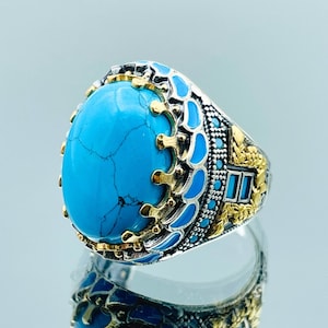 May include: A silver ring with a large turquoise stone set in a gold crown design. The ring is decorated with intricate details and blue enamel.