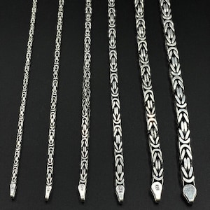 May include: Five silver chains of varying lengths, each with a distinct box clasp. The chains are all made of the same type of metal and have a similar design.
