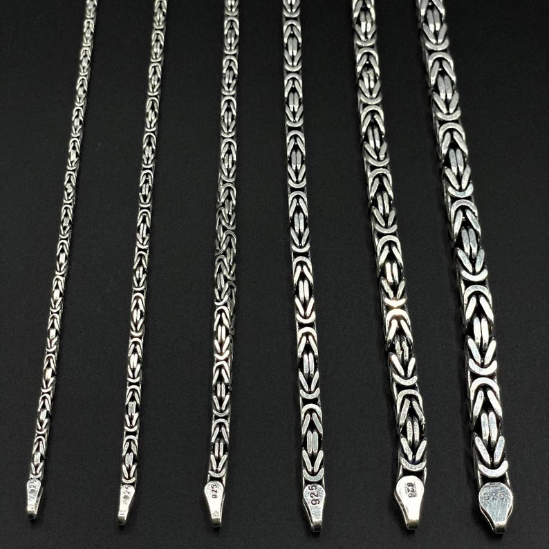 May include: Five silver chains of varying lengths, each with a distinct box clasp. The chains are all made of the same type of metal and have a similar design.