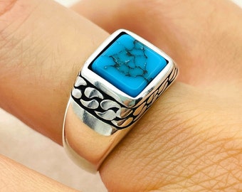 May include: A silver ring with a square turquoise stone set in a decorative band.