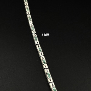 May include: A silver-colored chain bracelet with a repeating pattern of white and green oval-shaped links. The bracelet is 4 mm wide and is displayed against a black background.