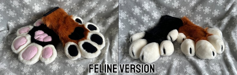May include: A pair of brown and black furry paw hand puppets with white paw pads and pink heart-shaped details. The puppets are on a gray and white snowflake patterned fabric.