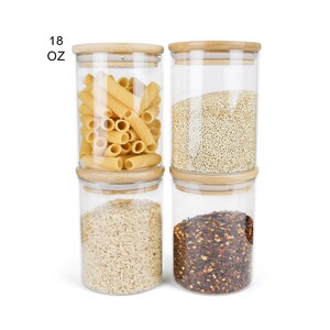 May include: Four glass jars with bamboo lids, each filled with different dry goods. The jars are labeled "18 OZ". The jars contain pasta, quinoa, rice, and red pepper flakes.
