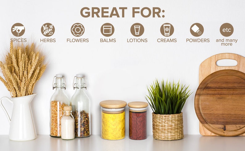 May include: Glass jars with wooden lids, filled with spices, herbs, and powders. The jars are on a white countertop with a wooden cutting board and a potted plant. The text "GREAT FOR:" is written on the wall above the jars, followed by a list of uses for the jars, including spices, herbs, flowers, balms, lotions, creams, powders, and more.