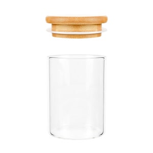 May include: A clear glass jar with a wooden lid. The lid has a white inner ring.