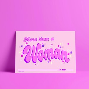 Puede incluir: Una tarjeta rosa con el texto "More than a Woman" en una fuente retro morada. El texto está rodeado de pequeñas flores de colores y signos de paz. La tarjeta tiene un espacio en blanco para escribir y el texto "to me" en la parte inferior.