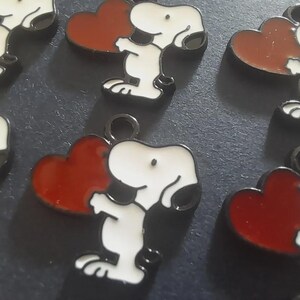 A lovely pack of eight Snoopy the dog with love heart pendant charms.