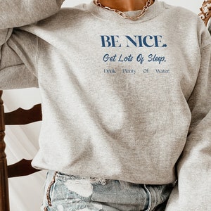 May include: A gray sweatshirt with the text "BE NICE. Get Lots Of Sleep. Drink Plenty Of Water." printed in blue.