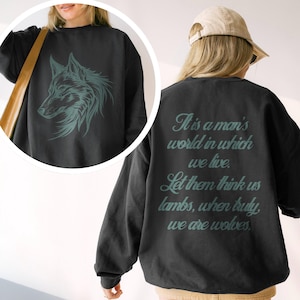 May include: Black sweatshirt featuring a teal wolf head graphic on the front and a quote on the back: "It is a man's world in which we live. Let them think us lambs, when truly, we are wolves."