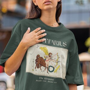 May include: A green t-shirt with a vintage illustration of the Sagittarius constellation and the text "Sagittarius, The Adventurer, November 22nd - December 21st".