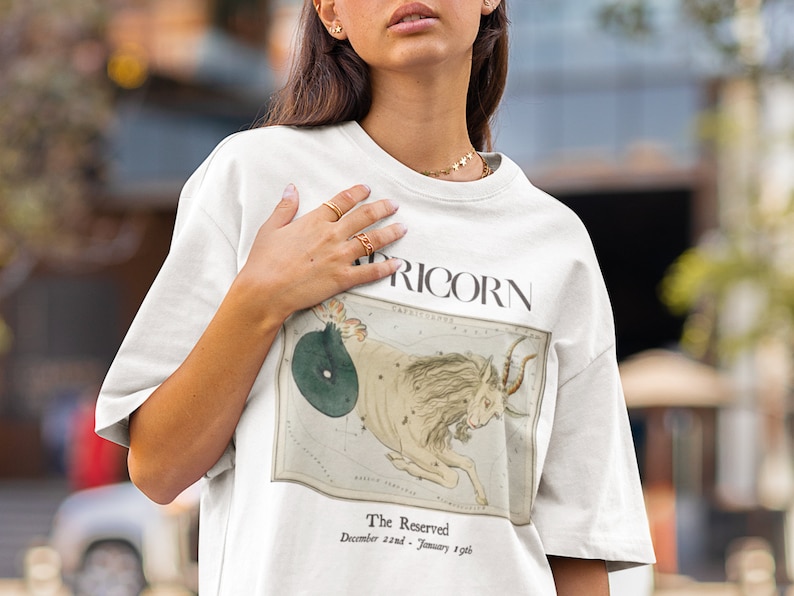 May include: White t-shirt with a vintage illustration of the Capricorn constellation and the text "The Reserved - December 22nd - January 19th" printed on the front.