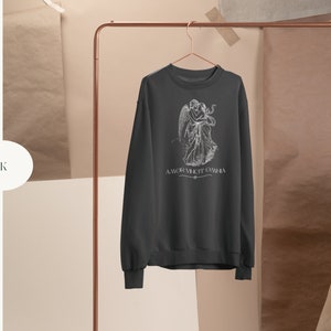 May include: Black sweatshirt with a white graphic print of two angels embracing. The text "AMOR VINCIT OMNIA" is printed below the graphic.