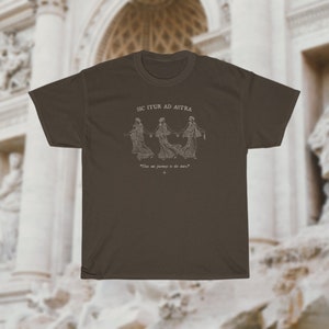 May include: A dark brown t-shirt with a white graphic of three figures holding hands and the text "Sic Itur Ad Astra" and "Thus we journey to the stars".