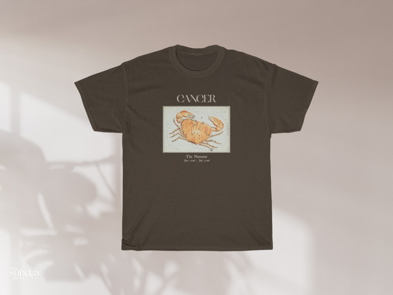 May include: A dark brown t-shirt with a graphic of the Cancer zodiac sign, a crab, and the text "Cancer, The  Nurturer, June 21st - July 22nd".
