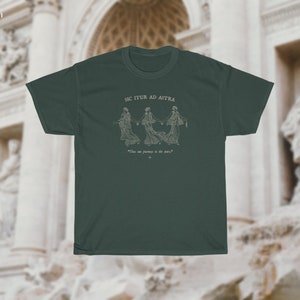 May include: A forest green t-shirt with a white graphic of three figures holding hands and the text "Sic Itur Ad Astra" and "The one journey is the dare".