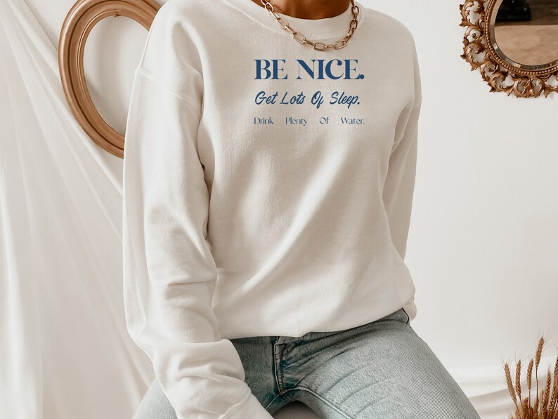 May include: White sweatshirt with blue text that reads "BE NICE. Get Lots Of Sleep. Drink Plenty Of Water."