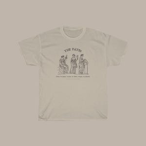 May include: A white t-shirt with a graphic of three women representing the Fates, with the text "THE FATES" above the image and "Clotho the spinner, Lachesis the allotter, Atropos the inflexible" below the image.