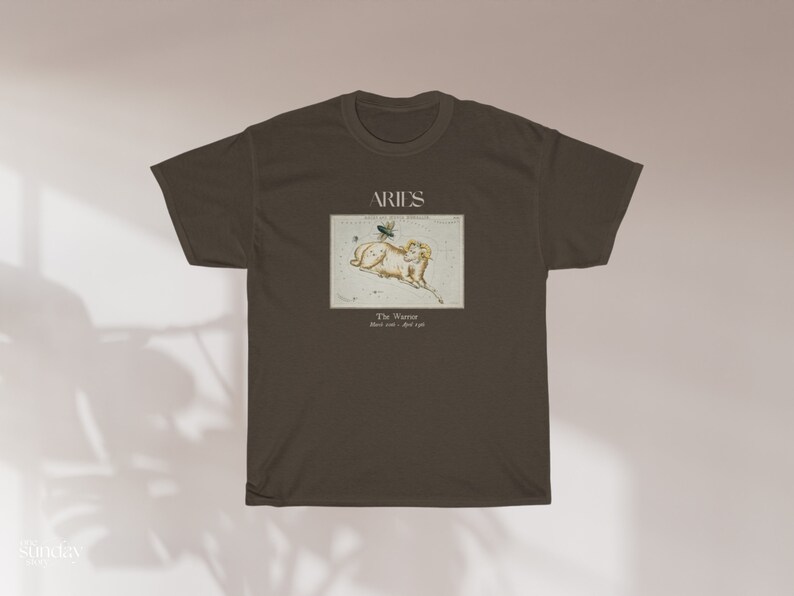 Pu&ograve; includere: Una maglietta marrone con un'illustrazione vintage della costellazione dell'Ariete. L'illustrazione &egrave; in una cornice bianca con il testo "Aries The Ram March 21 - April 19".